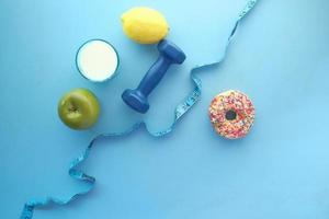 measuring tape wrapped around a dumbbell and donuts on table photo