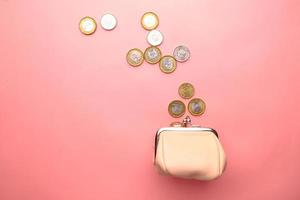 Vista superior de monedas en una pequeña bolsa de cuero en rosa. foto