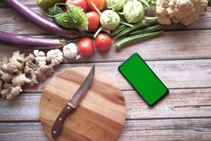 fresh vegetables, cutting board and smart phone on table photo