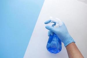 Mano en guantes de goma azul sosteniendo una botella de spray con espacio de copia foto