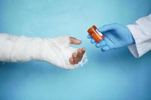 El médico recomienda medicamentos para la mano dolorosa lesionada con vendaje.