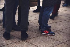 Mens' legs with footwear standing on pavement photo