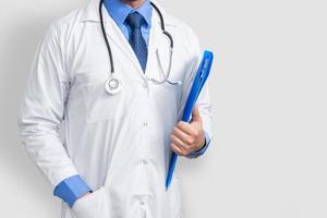 Doctor en bata de laboratorio sosteniendo el expediente del paciente o notas médicas, aislado sobre fondo blanco. foto