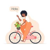 Una mujer joven monta una bicicleta con un ramo de flores en una canasta. vector