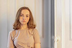 una linda chica joven y elegante está sentada en la puerta de su habitación foto