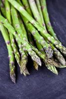 Primer plano de espárragos orgánicos frescos crudos de jardín sobre fondo de tablero negro. verduras de primavera verde. foto