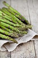 Bunch of fresh raw garden asparagus closeup and linen napkin on rustic wooden table background. photo