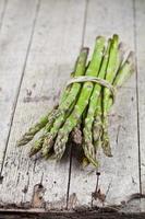 Bunch of fresh raw garden asparagus on rustic wooden table background. Green spring vegetables. photo