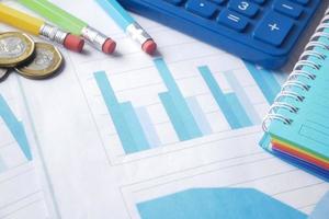 Financial graph, calculator and notepad on table photo