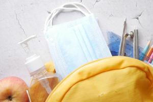 Student school backpack with school stationary and face mask on table photo