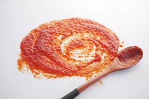 Tomato sauce and wooden spoon on white background photo