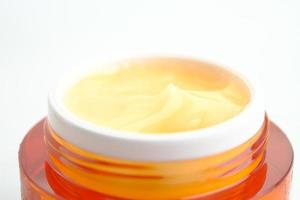 Close up of face cream in a orange container isolated on white background photo