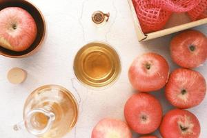 Vinagre de manzana en botella de vidrio con manzana roja fresca en la mesa foto