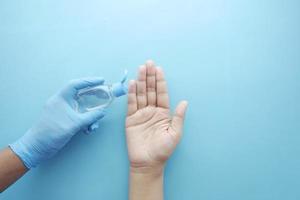 Using sanitizer liquid for preventing corona virus on blue background photo