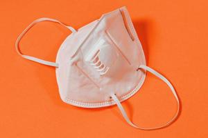 Medical mask with valve and surgical mask on orange background photo