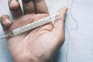 Man's hand holding medical thermometer photo