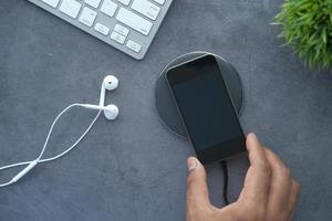 Man's hand charging smartphone using wireless charging pad, top view photo