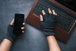 Hacker's hand stealing data from laptop, top down view photo