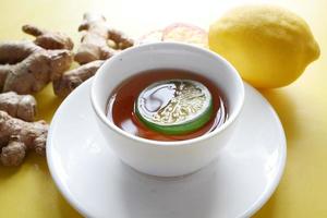 Close up of lemon tea and ginger on yellow background photo