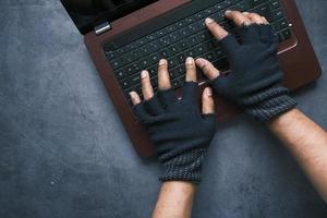 Hacker's hand stealing data from laptop, top down view photo