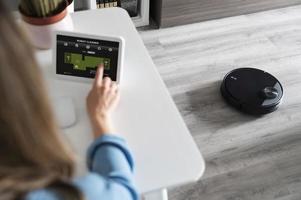 Woman activating robot cleaner photo