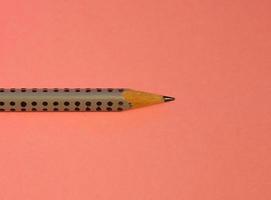 A simple pencil on a pink background photo