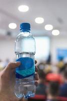 Business man on conference holding and drinking watter bottle. photo