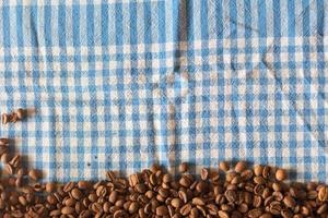 Granos de café sobre la mesa con un paño de gangham checkere foto