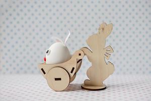A wooden rabbit carries a cart with an egg with bunny ears photo