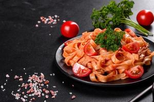 Deliciosa pasta fresca con salsa de tomate con especias y hierbas sobre un fondo oscuro
