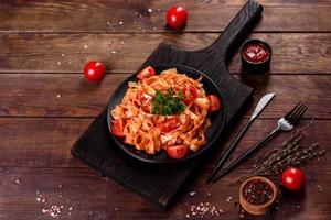 Deliciosa pasta fresca con salsa de tomate con especias y hierbas sobre un fondo oscuro