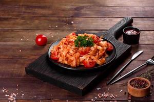 Delicious fresh paste with tomato sauce with spices and herbs on a dark background photo