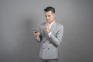 Businessman is using smart phone, portrait in studio grey background photo