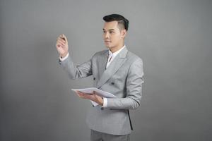 Businessman is writing business goal, grey background photo