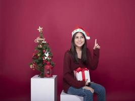 hermosa niña de santa claus en estudio sobre fondo rojo, concepto de navidad foto