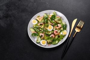 Salad with shrimp, avocado, cucumber, pumpkin seeds and flax seeds with olive oil photo