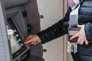 Female hands hold a plastic bank credit card, use an ATM machine photo