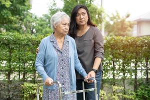 Ayude y cuide a la anciana asiática mayor o anciana que use un andador con una salud fuerte mientras camina en el parque en felices vacaciones frescas.