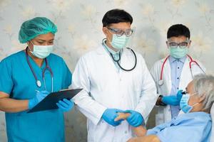 El equipo de médicos asiáticos revisa a la anciana paciente mayor en busca de enfermedad para motivarla a tratar la infección por coronavirus covid-19 en la sala del hospital. foto