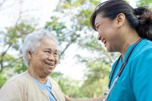 médico ayuda y cuidado anciana asiática mayor o anciana con una salud fuerte mientras camina en el parque en felices vacaciones frescas. foto