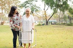 Ayude y cuide a la anciana asiática mayor o anciana que use un andador con una salud fuerte mientras camina en el parque en felices vacaciones frescas.