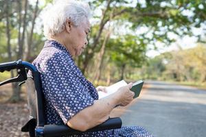 Paciente asiático mayor o mayor de la mujer de la señora mayor que lee un libro mientras está sentado en la cama en la sala del hospital de enfermería, concepto médico fuerte y saludable.