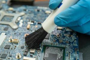 Technician use brush and air blower ball to clean dust in circuit board computer. Repair upgrade and maintenance technology. photo