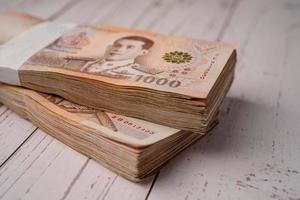 Stack of Thai baht banknotes on wooden background, business saving finance investment concept. photo