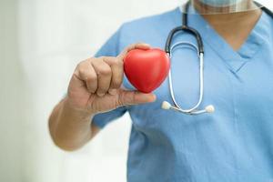 Paciente asiático mayor o anciano mujer sosteniendo un corazón rojo en su mano en la cama en la sala del hospital de enfermería, concepto médico fuerte y saludable foto