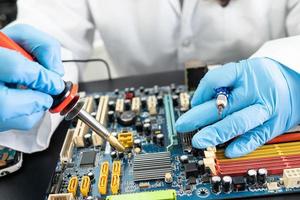 E-waste, technician repairing inside of hard disk by soldering iron. Integrated Circuit. the concept of data, hardware, technician and technology. photo