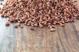 Granos de cacao crudo en una mesa de madera foto