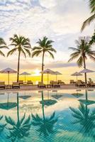 Umbrella and chair around swimming pool in hotel resort with sunrise in morning photo