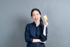 Portrait of a lovely young Asian woman showing credit card photo