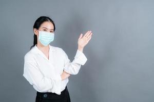 Mujer asiática con mascarilla médica protege el polvo del filtro pm2.5 anti-contaminación, anti-smog y covid-19 con presentación de la mano foto